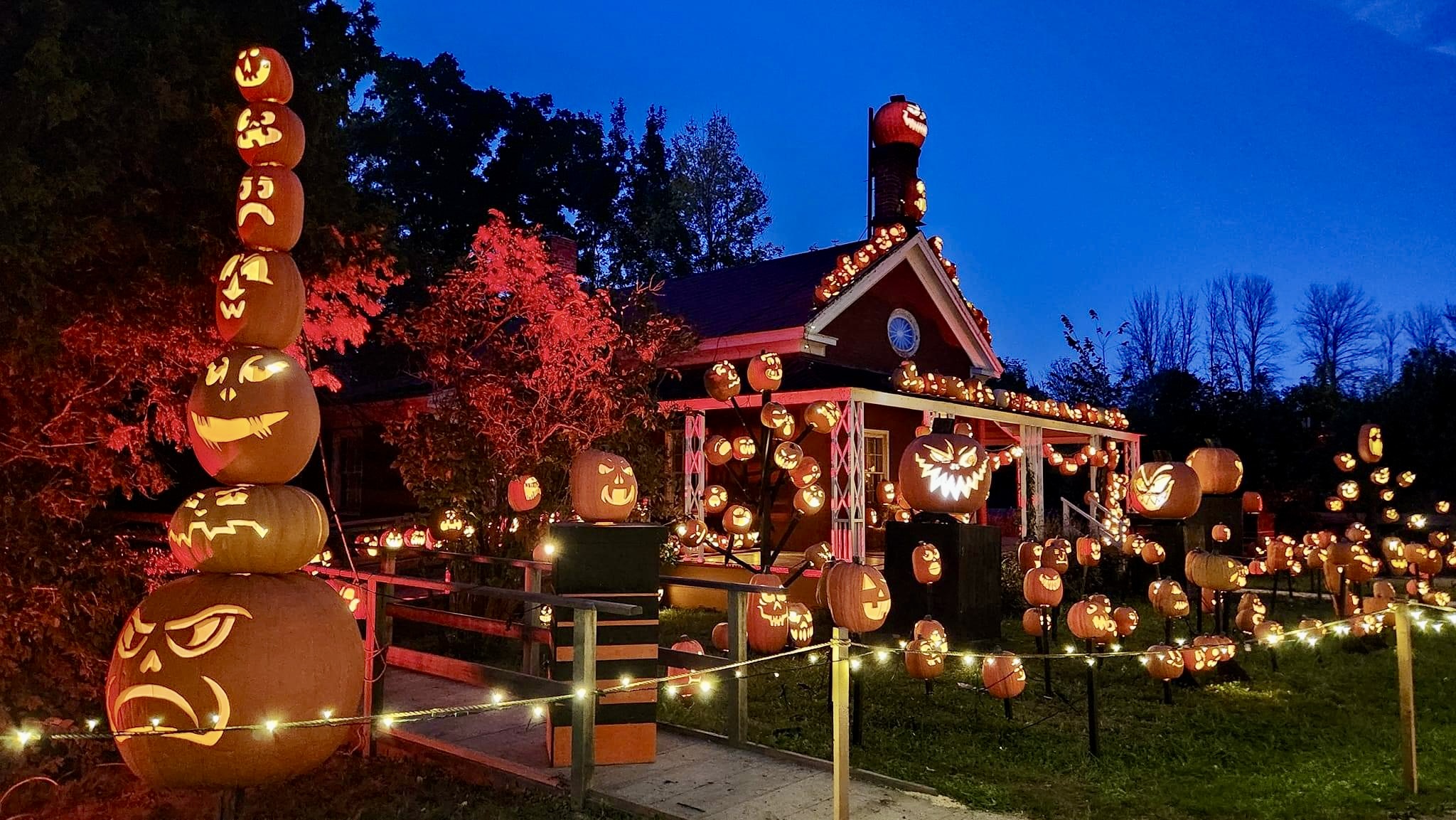 Historic house decorated with hundreds of glowing pumpkins under the night sky.